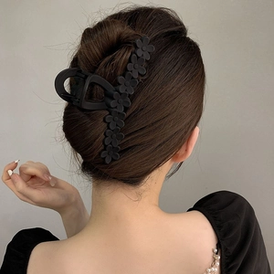 Matte black 13cm shark hair clip with elegant floral accents on model hair