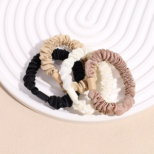 Set of 4 pleated satin scrunchies in black, beige, white, and brown on a white tray
