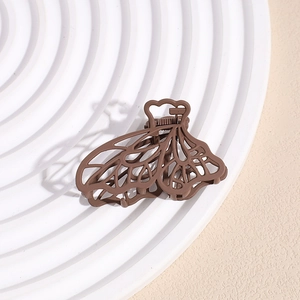 Detail of a brown matte butterfly hair claw with hollow lines on a white pedestal