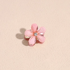 Makroaufnahme einer kleinen rosa Kamelien-Haarklammer mit Goldglitzer und einem Strassstein