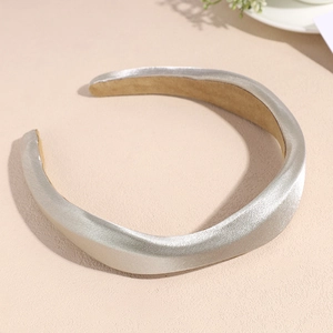 Détail d'un serre-tête rembourré or champagne avec tissu métallique et doublure antidérapante