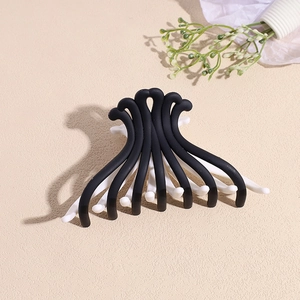 Détail de la pince à cheveux mate noire et blanche sur une surface beige texturée