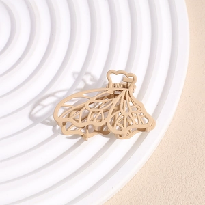 Detail of matte beige butterfly hair claw clip with elegant hollow wings on minimalist stand