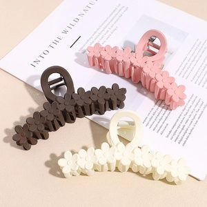 Set of three matte floral claw clips in pink, cream and brown on a lifestyle background