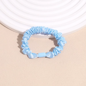 Close-up of light blue satin scrunchie with soft silk luster and pleated texture