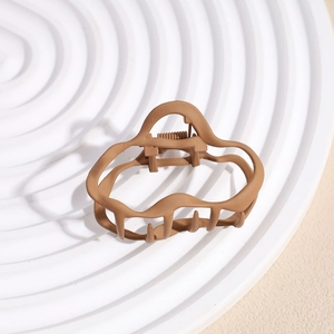Detail of matte brown hair claw clip featuring a wave design and sturdy metal spring