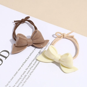 Elegant floral bow hair ties in brown and cream colors on a vintage book background