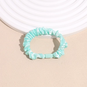 Detail of mint green pleated silk scrunchie with modern square plastic connector link