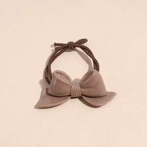 Detail of a brown bow-knot hair tie featuring high-elasticity braided rope and smooth resin