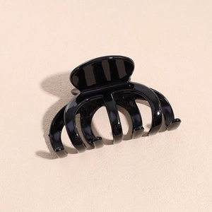 Gros plan d'une pince à cheveux pieuvre noire brillante sur un fond rose doux