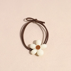 Detail of high-elasticity brown hair tie featuring a cream white floral ornament
