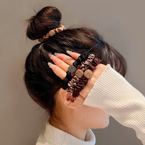 Leopard print and satin hair scrunchies with rhinestone charms on model's ponytail