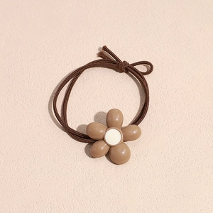 Detail view of a brown elastic hair tie featuring a coffee-colored floral acrylic ornament