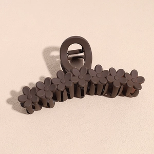 Macro detail of brown matte hair claw clip featuring small floral decorative elements