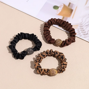 Three-piece set of satin scrunchies in black, brown, and leopard print with crystal beads