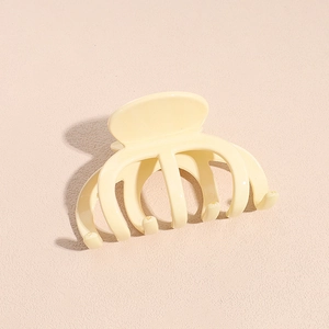 Détail d'une pince à cheveux pieuvre beige crème avec finition brillante sur fond neutre