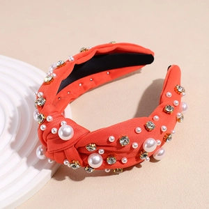 Close-up of orange knot headband with white faux pearls and sparkling rhinestones