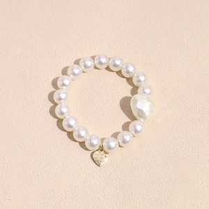 Detalle de coletero de perlas con colgante de corazón dorado y cuentas blancas