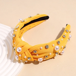 Close-up of yellow knotted headband with faux pearls and sparkling crystal rhinestones
