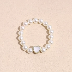 Vista detallada de una pulsera elástica de perlas con un colgante de corazón dorado