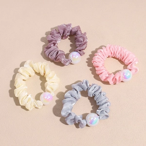 Detailed macro view of satin scrunchies featuring iridescent pearls in various soft colors