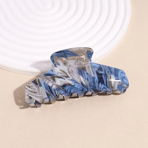 Dettaglio del fermaglio per capelli in acetato con motivo marmorizzato blu e bianco