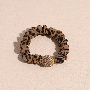 Detailed view of leopard print scrunchie with sparkling gold rhinestone ball charm