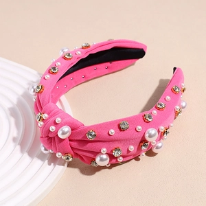 Close-up of rose pink knotted headband with white pearls and sparkling rhinestones