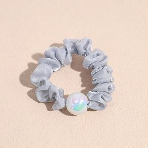 Detail showing smooth satin scrunchie texture and a large iridescent pearl accessory