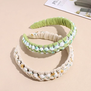 Serre-têtes tressés à fleurs vert et blanc en tissu sur un support beige
