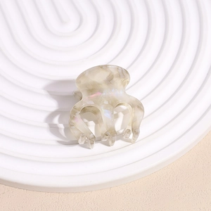 Gros plan détaillé d'une petite pince à cheveux en acétate marbré sur un plateau blanc
