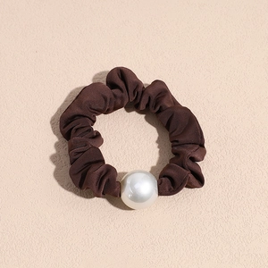 Macro shot of dark brown satin scrunchie with large white decorative pearl detail