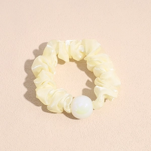 Detail of cream organza scrunchie with large pearlescent bead and ruffled edge