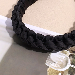 Détail d'un serre-tête en satin noir tressé avec une texture soyeuse élégante