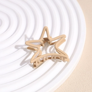 Macro detail of star-shaped matte hair claw clip in light brown on a textured display