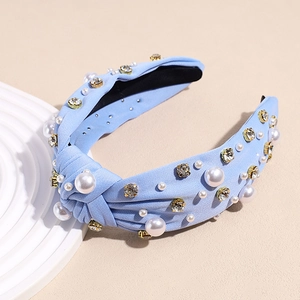 Detail of light blue knotted fabric headband with white pearls and sparkling rhinestones