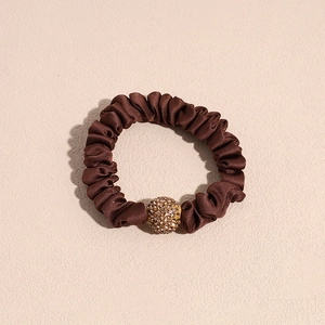 Detail of brown leopard print satin scrunchie featuring a sparkling gold rhinestone ball
