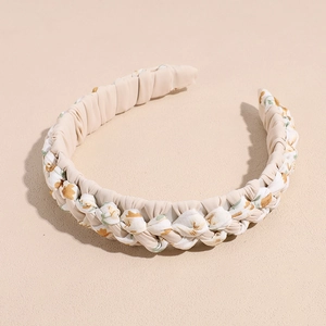 Détail du serre-tête tressé en tissu floral beige avec des motifs de petites fleurs