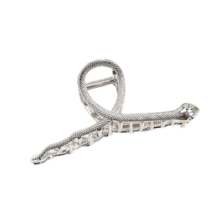 Pince à cheveux serpent argentée avec texture écailles et strass sur fond blanc