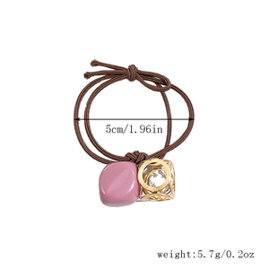 Close-up of brown elastic hair tie with crystal pendant showing 5cm diameter and 5.7g weight