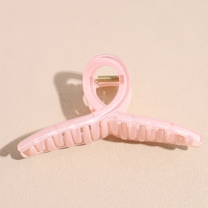 Détail d'une pince à cheveux rose translucide de 13cm avec un ressort en métal doré
