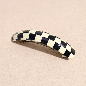 Detailed close-up of a black and white checkered acetate hair clip with silver metal grip