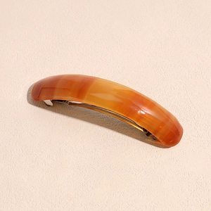 Detail view of tortoiseshell acetate spring hair clip with smooth amber texture