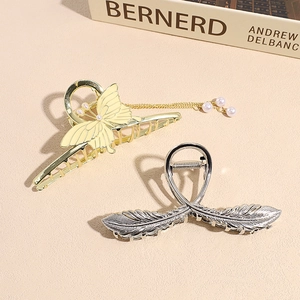 Elegant gold butterfly tassel hair claw and silver feather clip on a premium beige surface