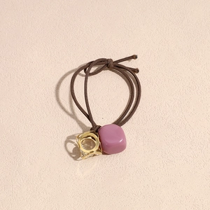 Detail of vintage brown hair tie with gold geometric hollow frame and faceted bead pendant