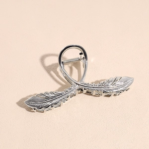 Detailed close-up of a silver feather hair claw clip with metallic texture and spring mechanism
