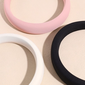 Three padded sponge headbands in pink, black, and white with ribbed fabric texture