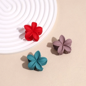 Trois pinces à cheveux fleur mates en rouge, turquoise et violet sur un présentoir blanc