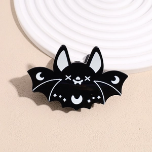 Macro shot of a black bat enamel hair clip with white star and moon details