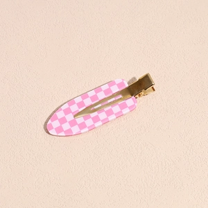 Vista macro dettagliata di un fermaglio per capelli a scacchi rosa e bianco con metallo oro